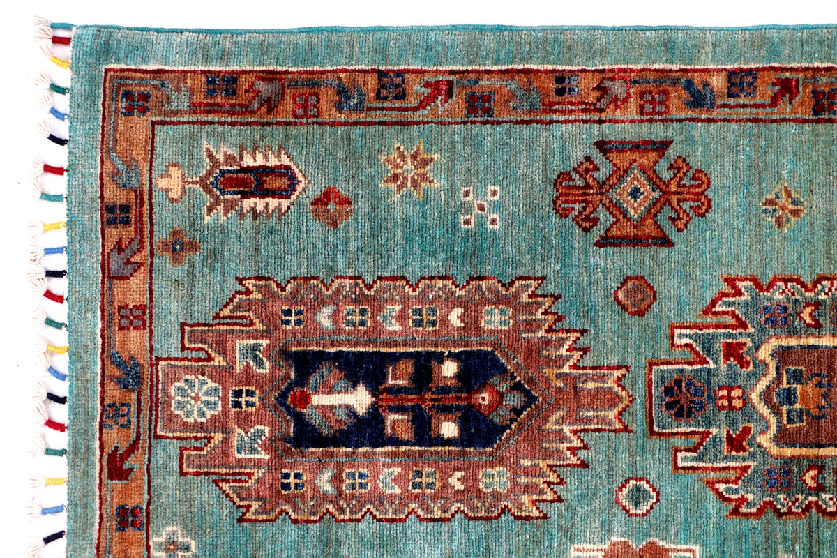 Turquoise rug with geometric medallion pattern, red accents, and fringed border