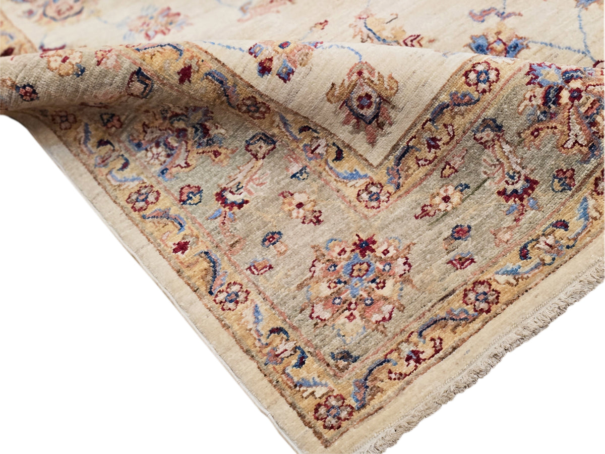 Corner detail on cream rug showing blue and red floral motifs and patterned border fringe