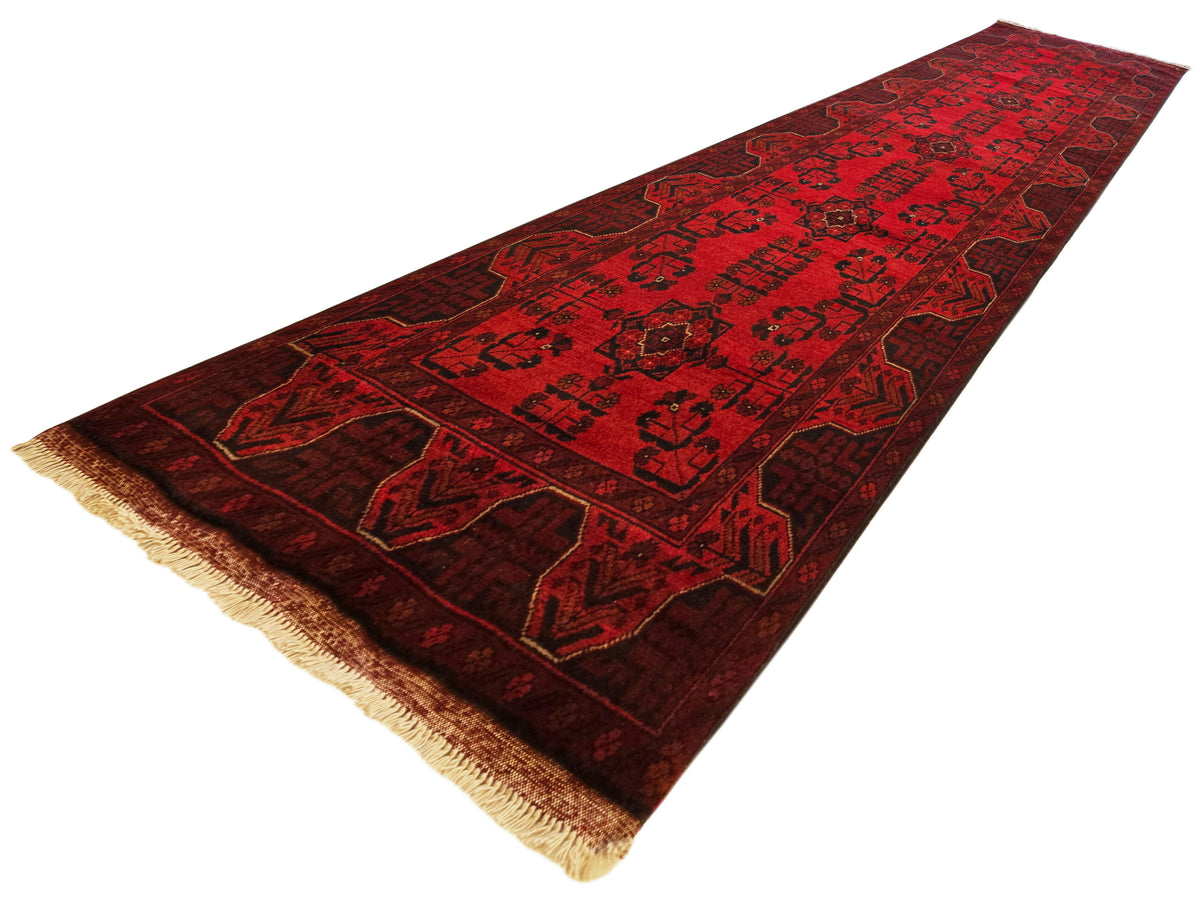 Red runner rug with dark geometric motifs and border, short tan fringe at ends