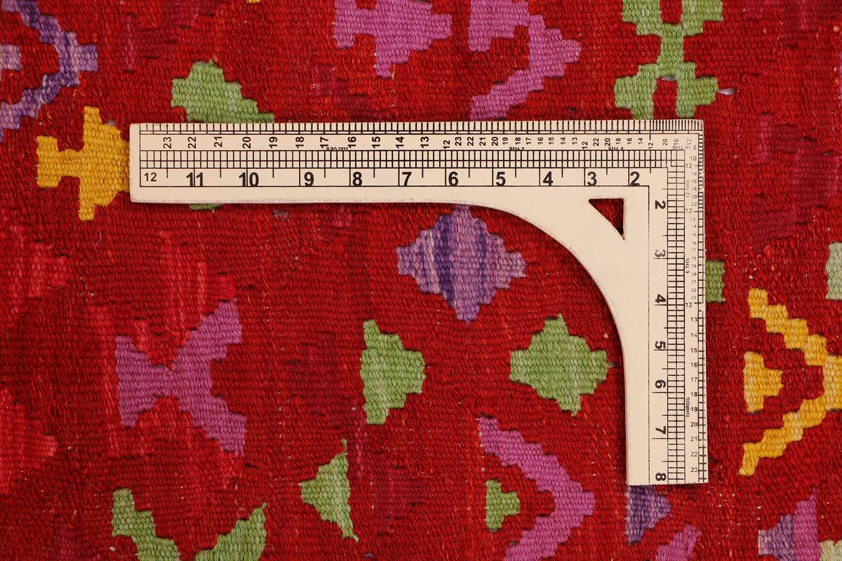 Crimson mosaic red kilim rug surface with multicolor pattern and measurement tape