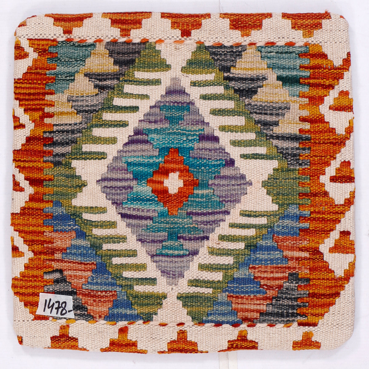 Kilim cushion cover close-up: orange border with multicolor geometric medallion on white