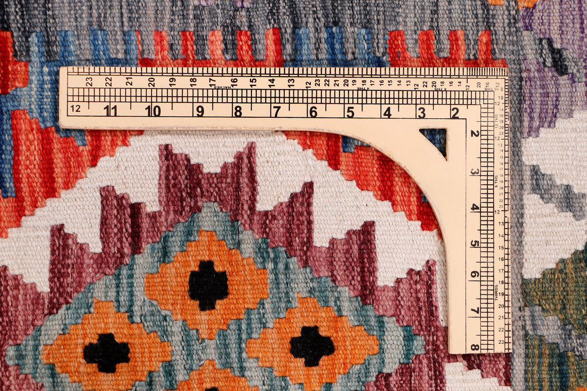 Kilim rug detail with multicolor pattern and measuring ruler along edge