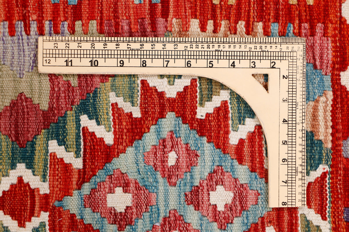 Kilim rug close-up with ruler measuring woven pattern in red, blue, and white
