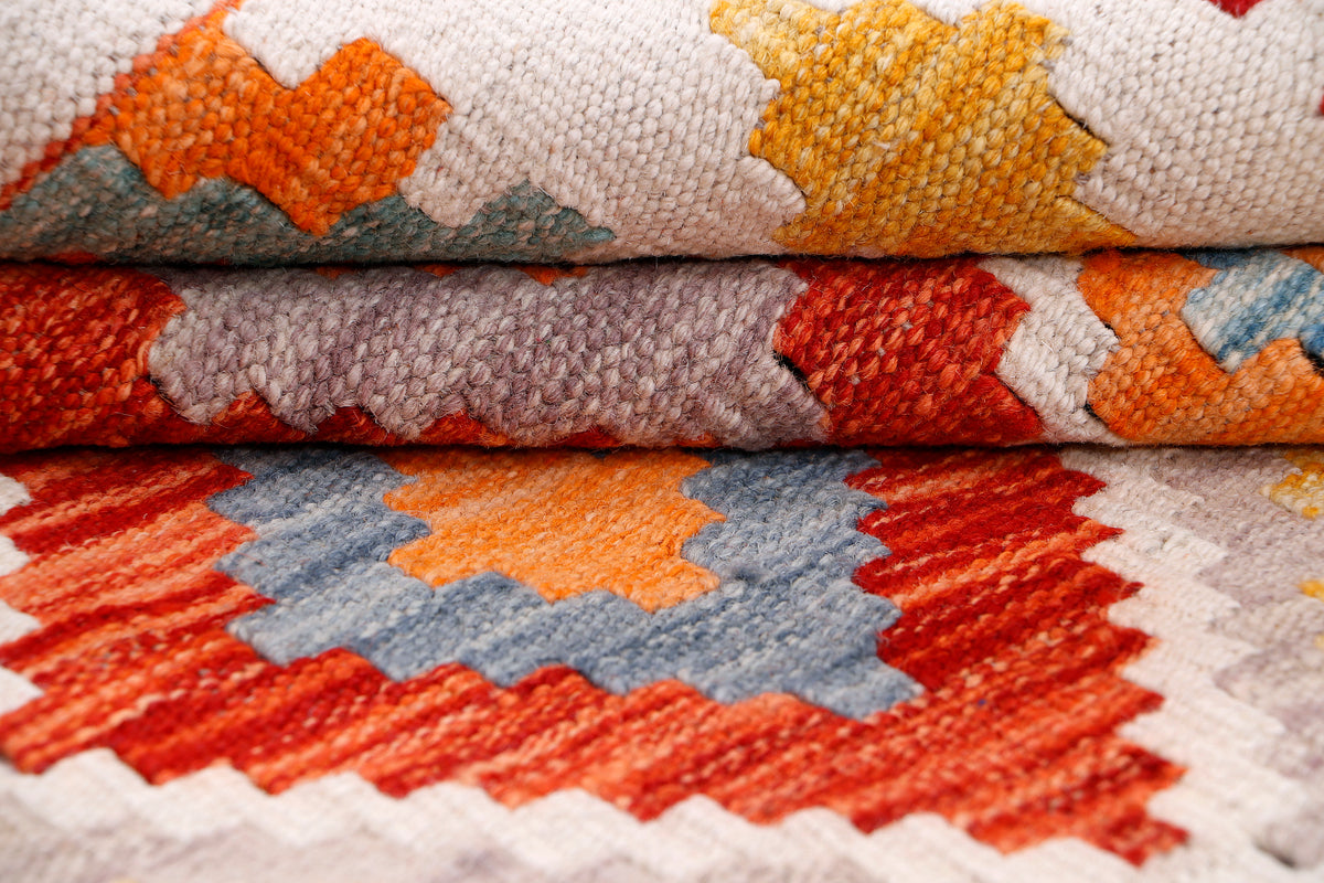 Red, orange, and blue kilim rug with geometric motifs, close-up weave detail.