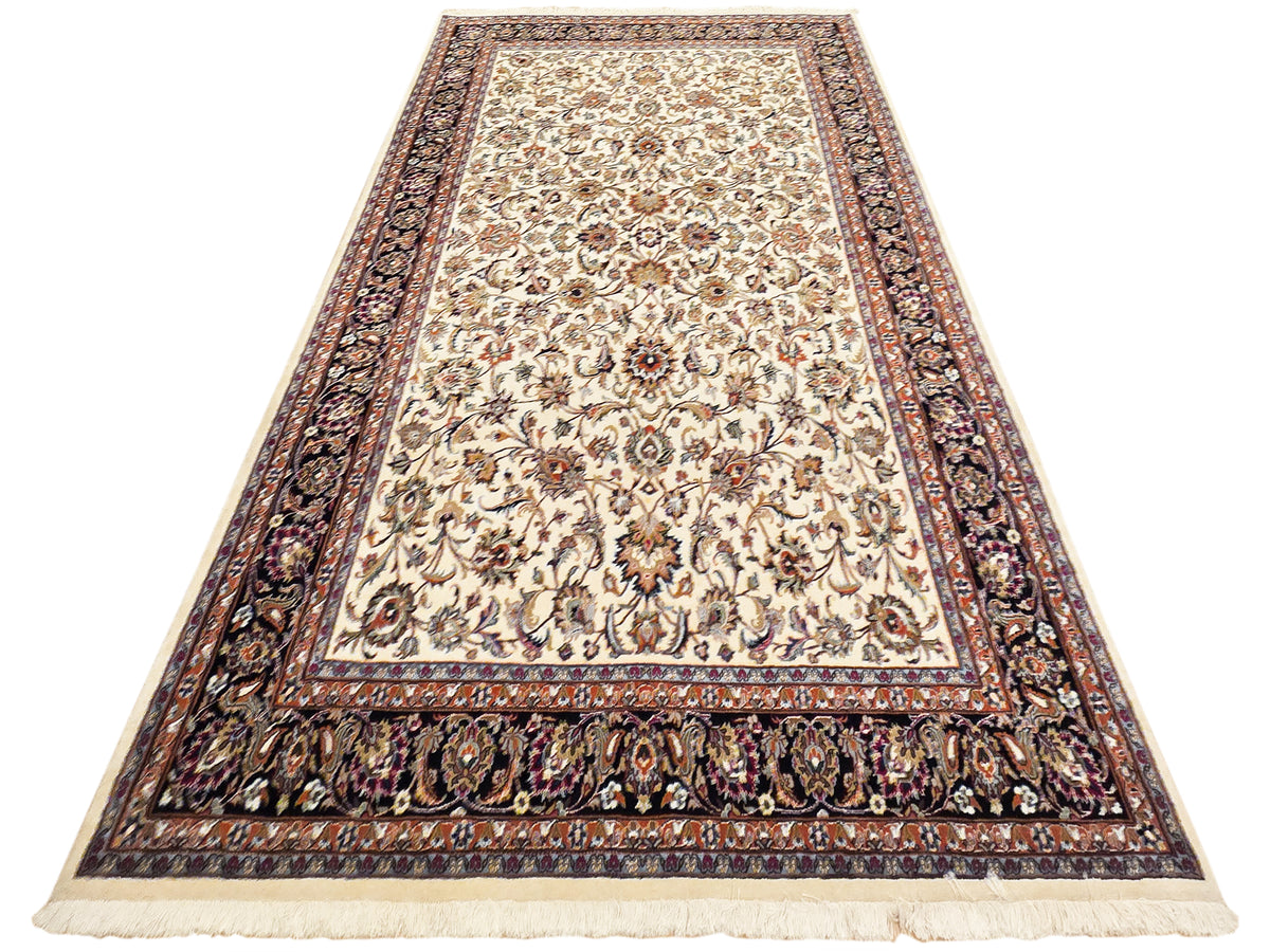 Cream floral area rug with navy patterned border and fringed ends