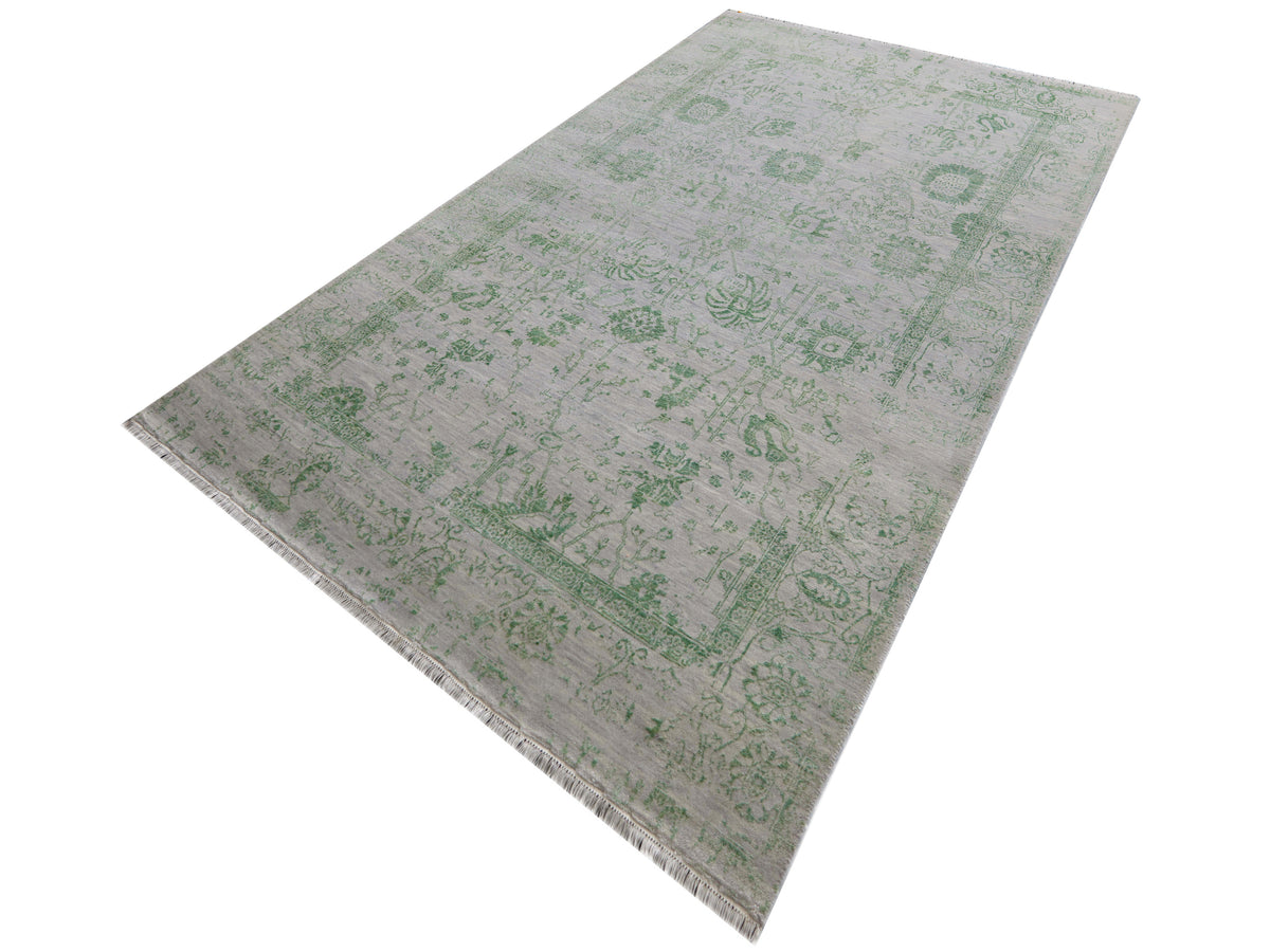 Light gray rug with green ornate motifs, short fringe on one side