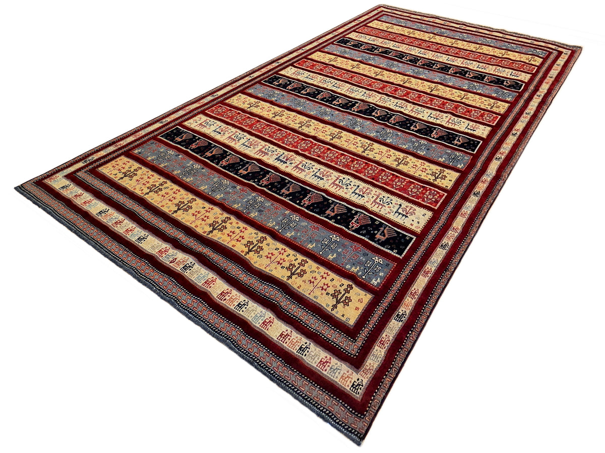 Diagonal view area rug with red center stripes, navy blocks, cream motifs and border