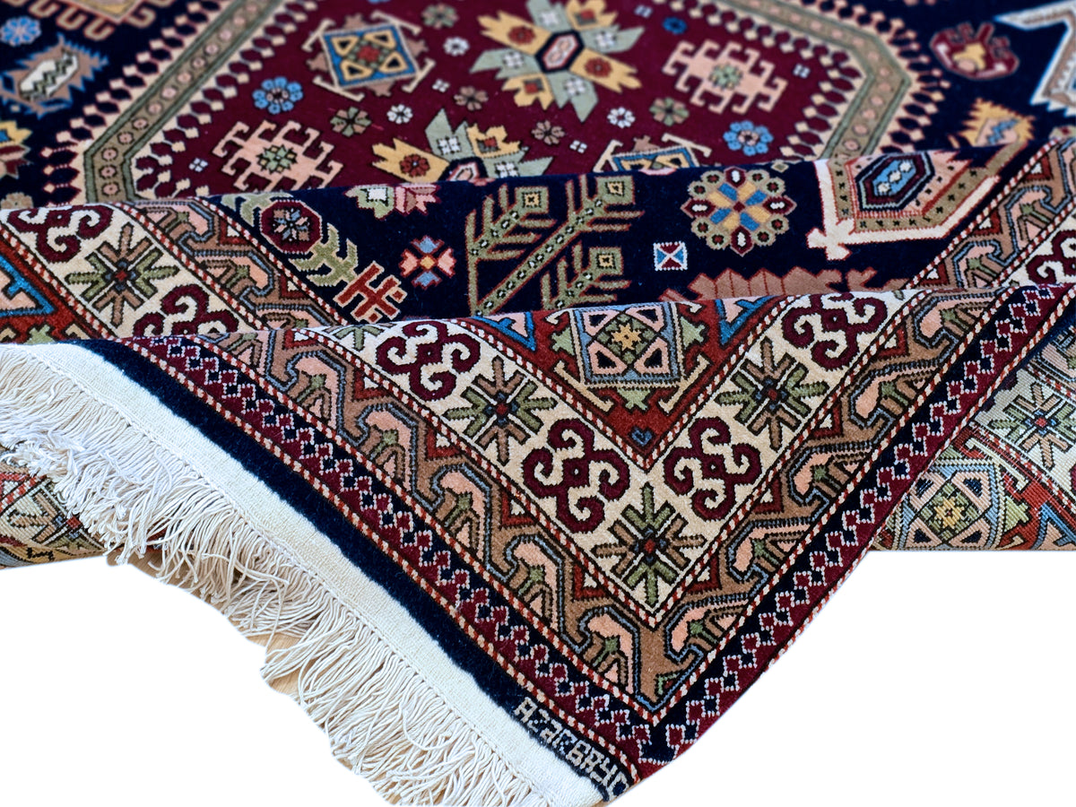 Azerbaijan rug corner detail with red, blue, cream motifs and white fringe