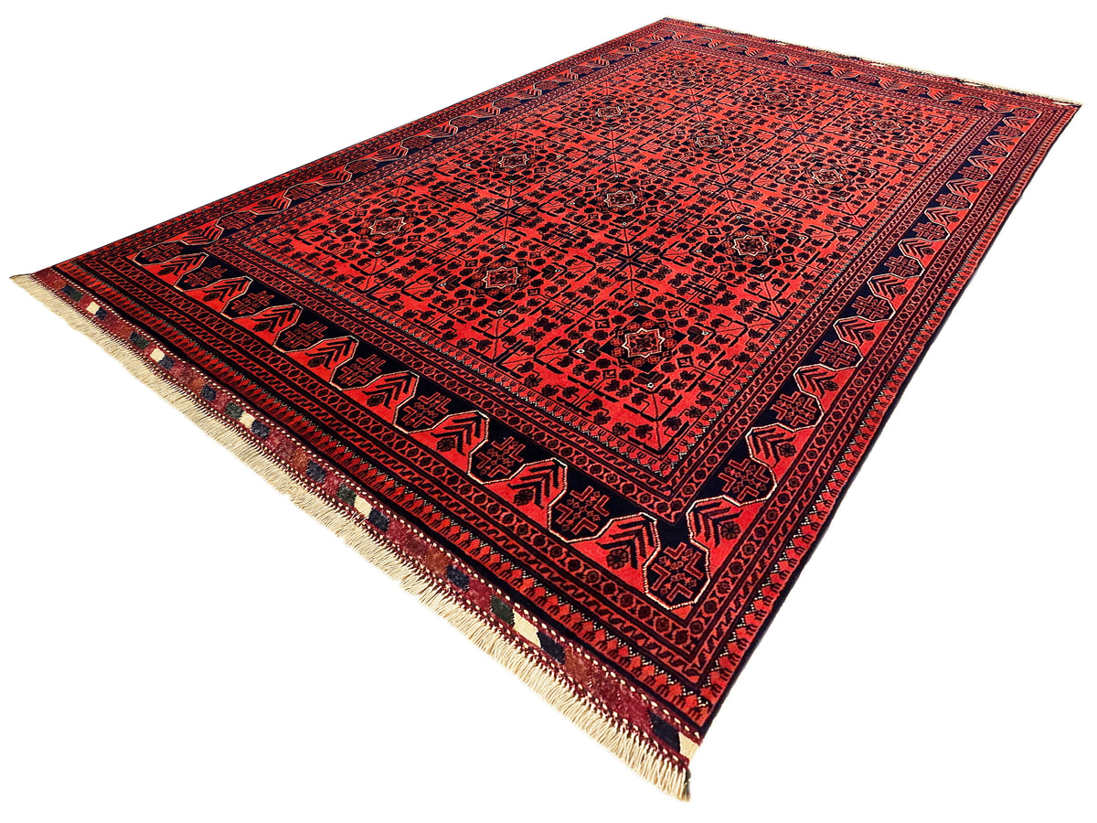 Red patterned rug with navy border and short beige fringe on edges