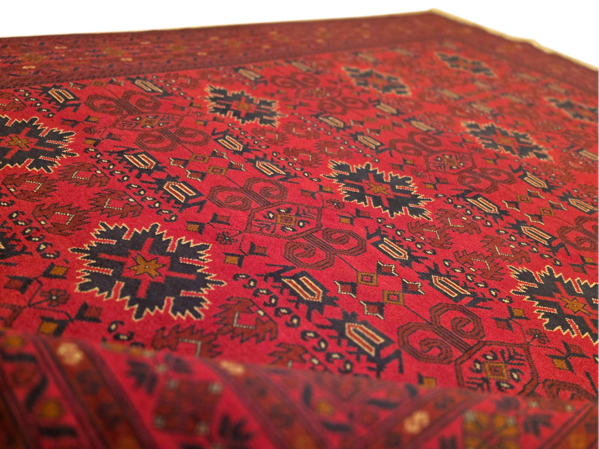 Red patterned area rug close-up with geometric motifs and dark outlining