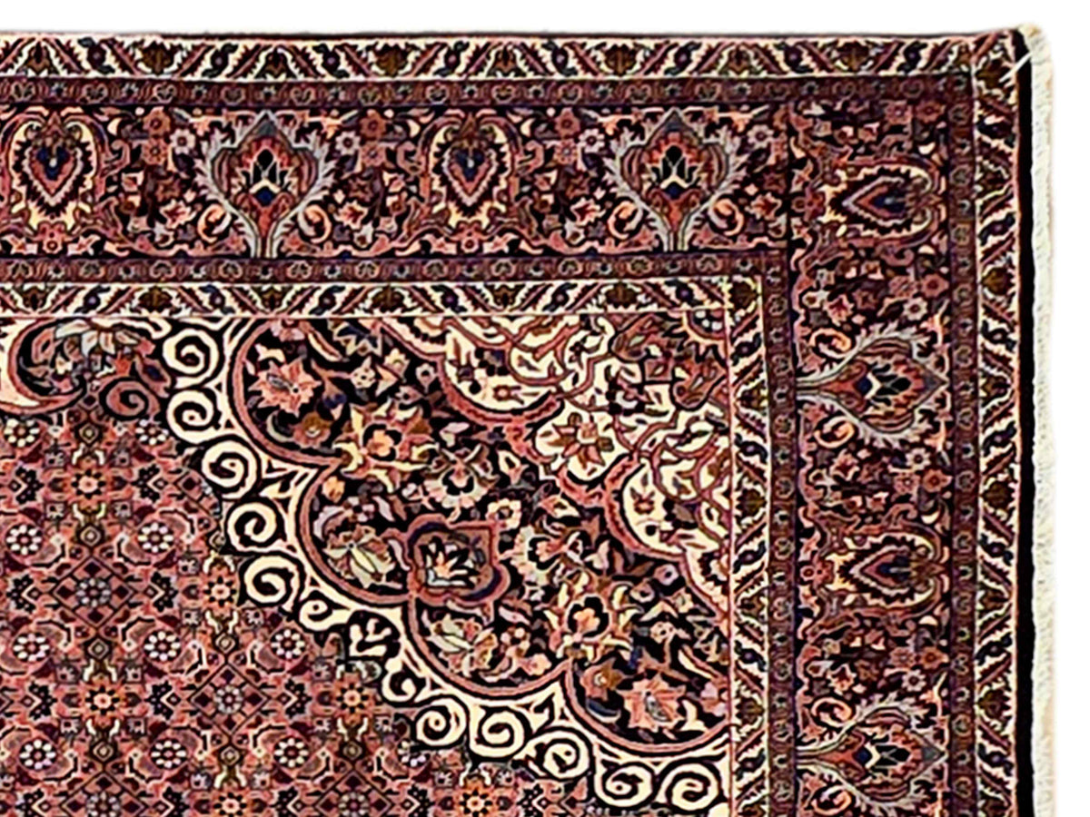 Detail view of terracotta area rug border with scrolling floral motifs