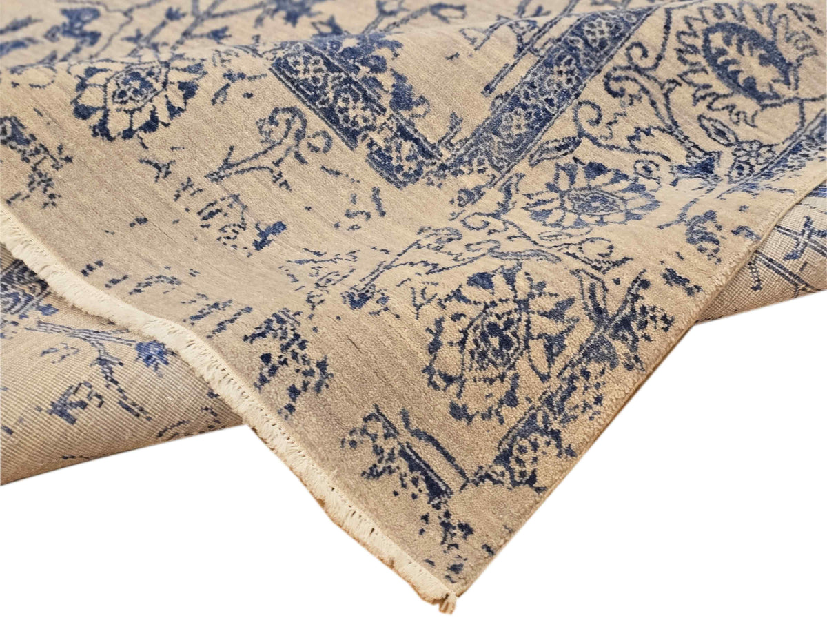 Beige and blue patterned area rug corner with distressed texture and trimmed edge.