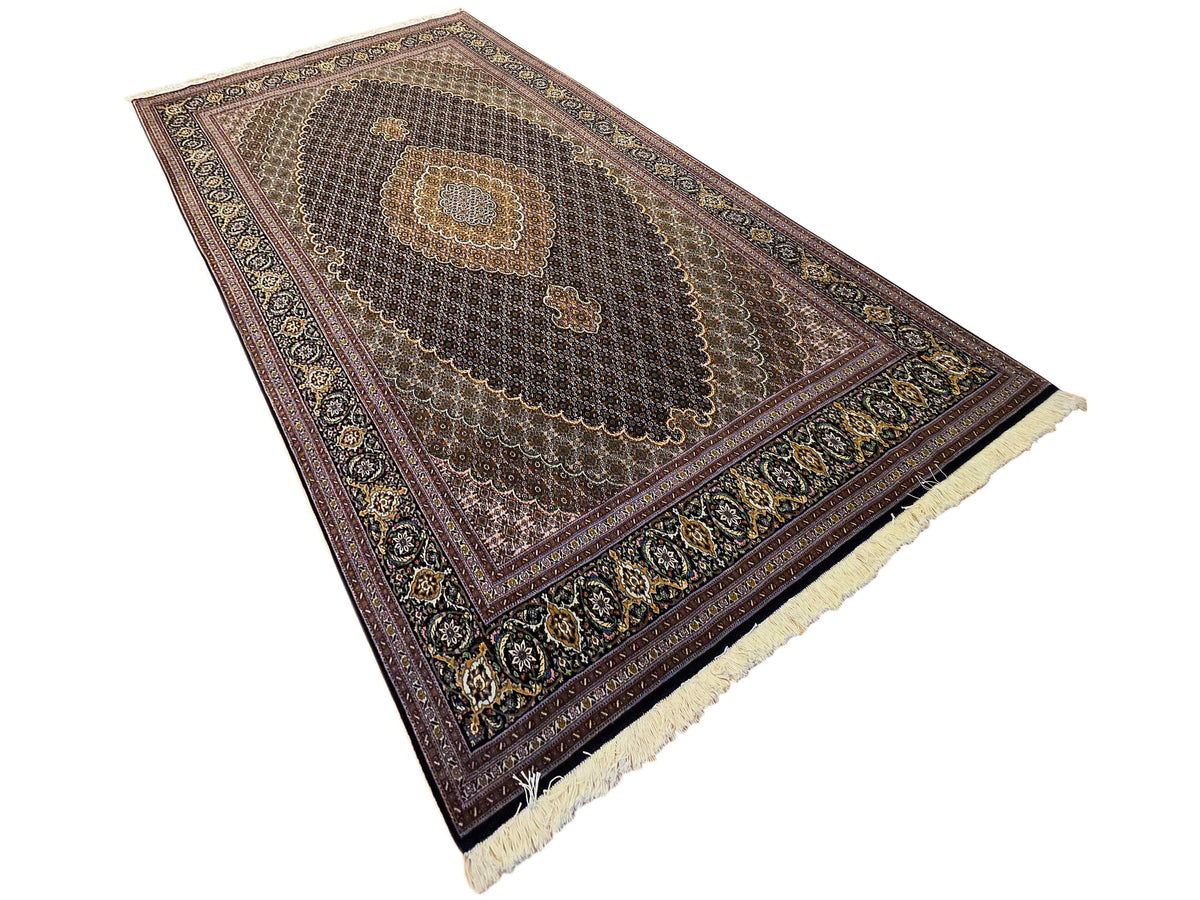 Dark Tabriz-style rug with central medallion and cream fringe along one edge