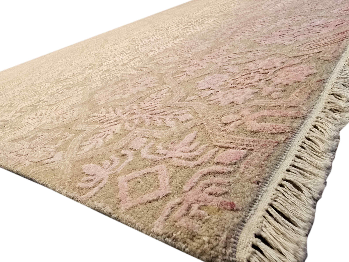 Beige area rug with soft pink and cream pattern and fringed edge
