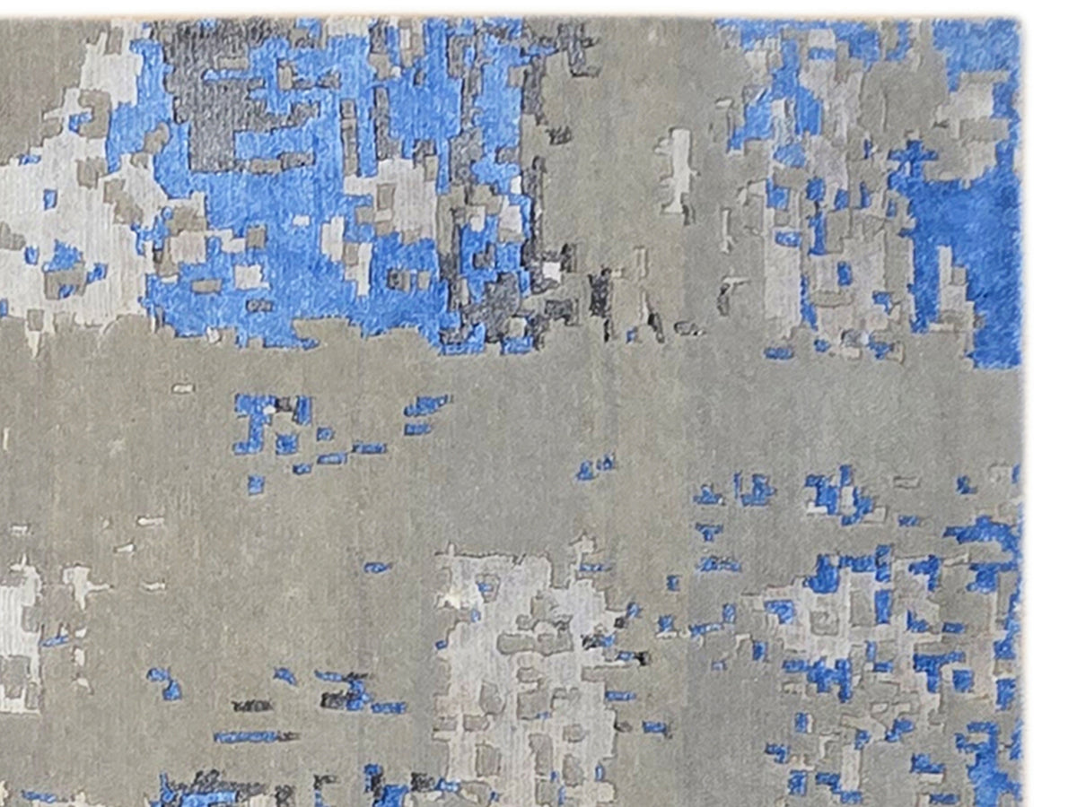 Gray rug with scattered blue abstract blocks and light speckles, tight close-up