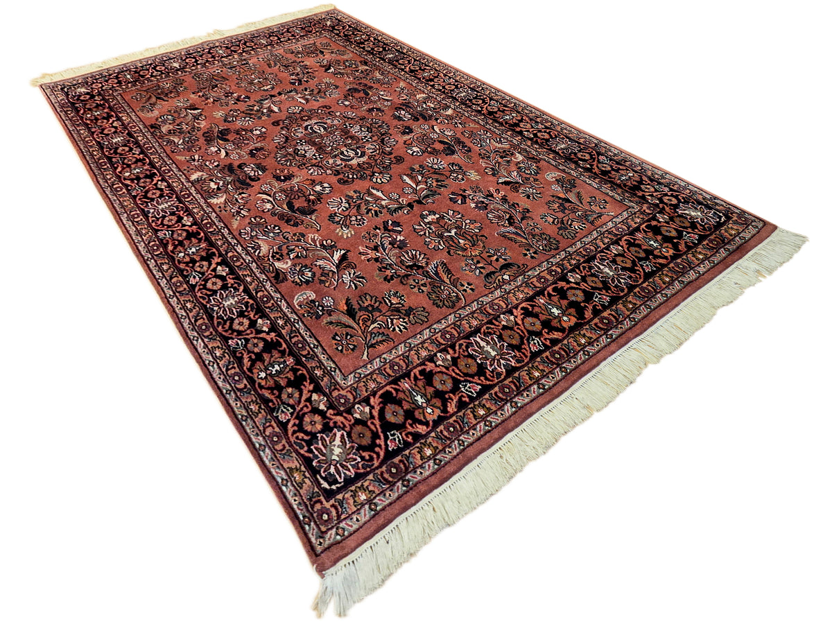 Terracotta Persian-style rug with dark floral medallion, ornate border, fringed ends