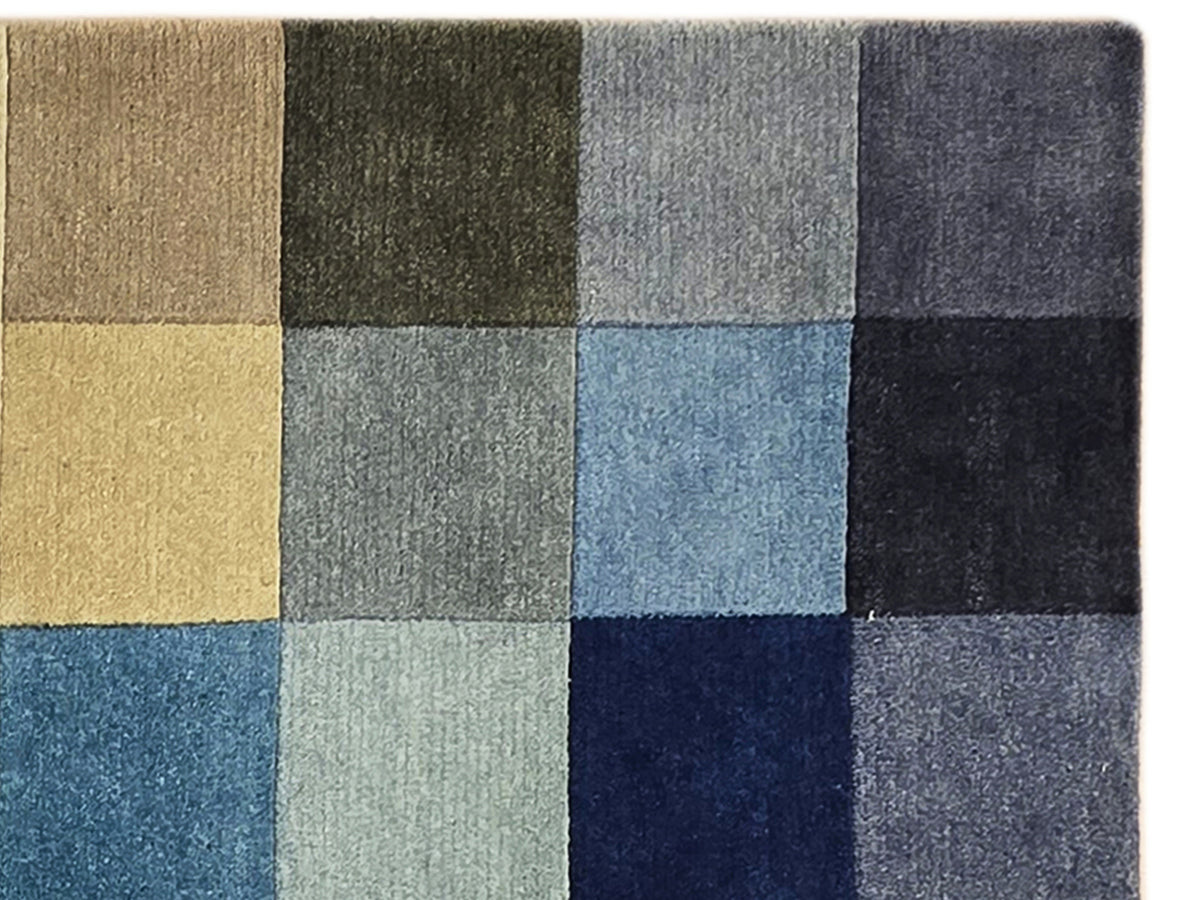 Multicolor rug edge with square blocks in black, gray, light blue, and mustard