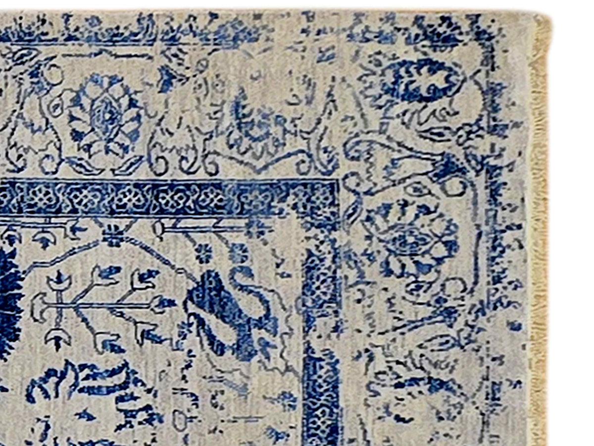 Close-up of blue ornamental motifs on cream rug with distressed texture
