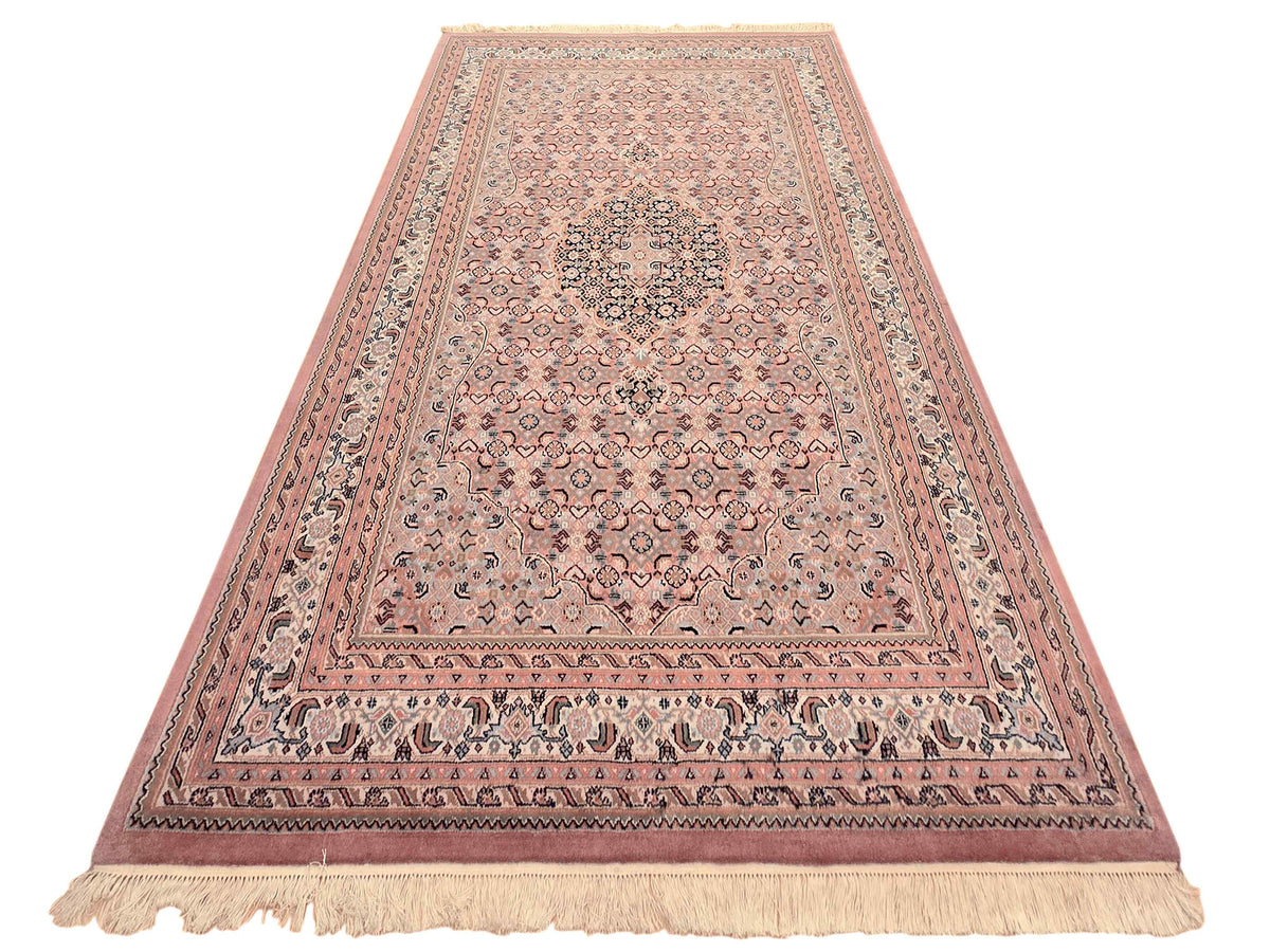 Bidjar rug wide view with dusty rose pattern, detailed border, and cream fringe trim
