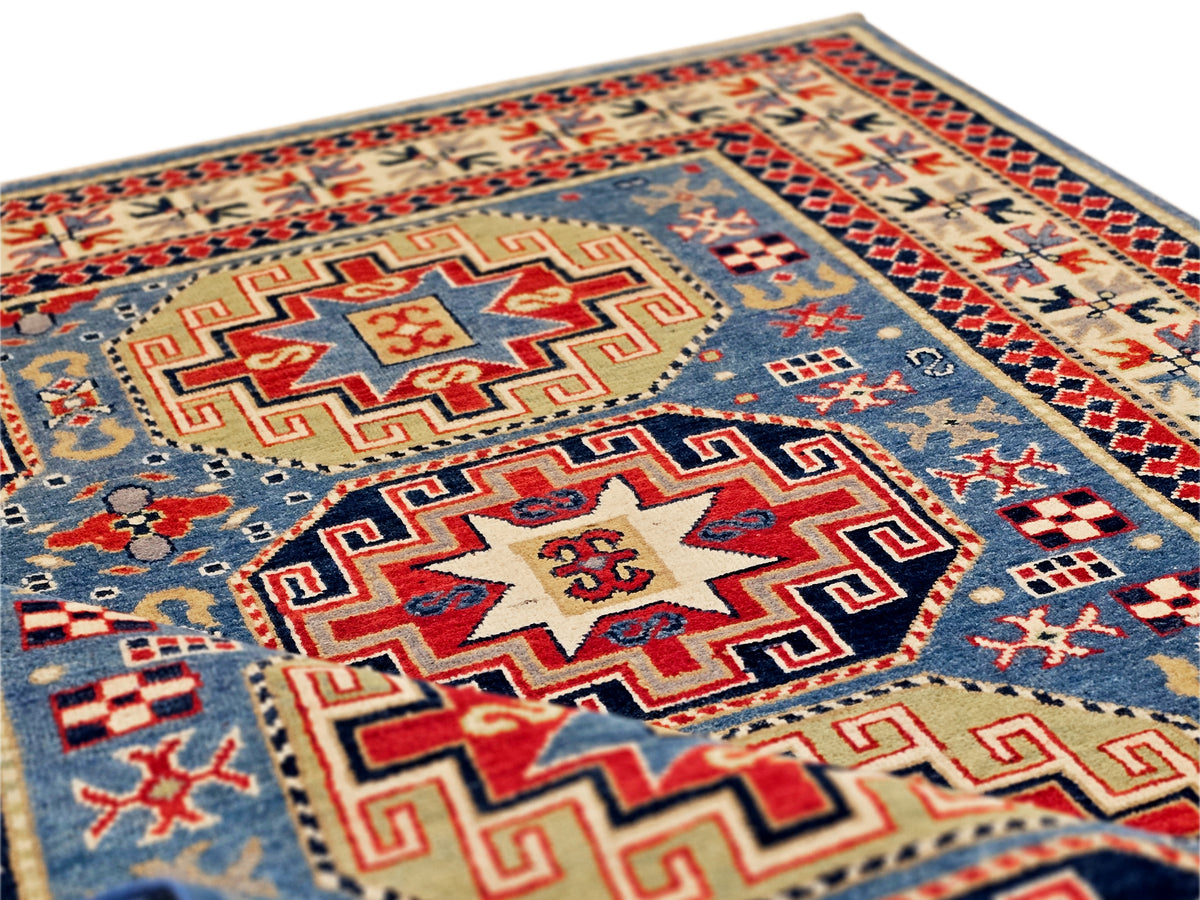 Kazak-style rug with blue field, red geometric medallion, and patterned border.