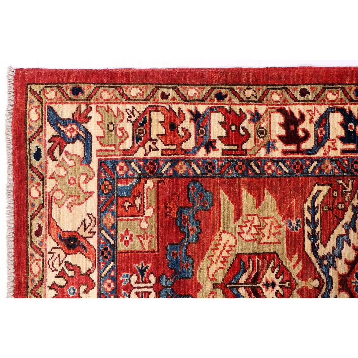 Close-up of red Kazak rug with repeating motifs in cream, navy, and blue