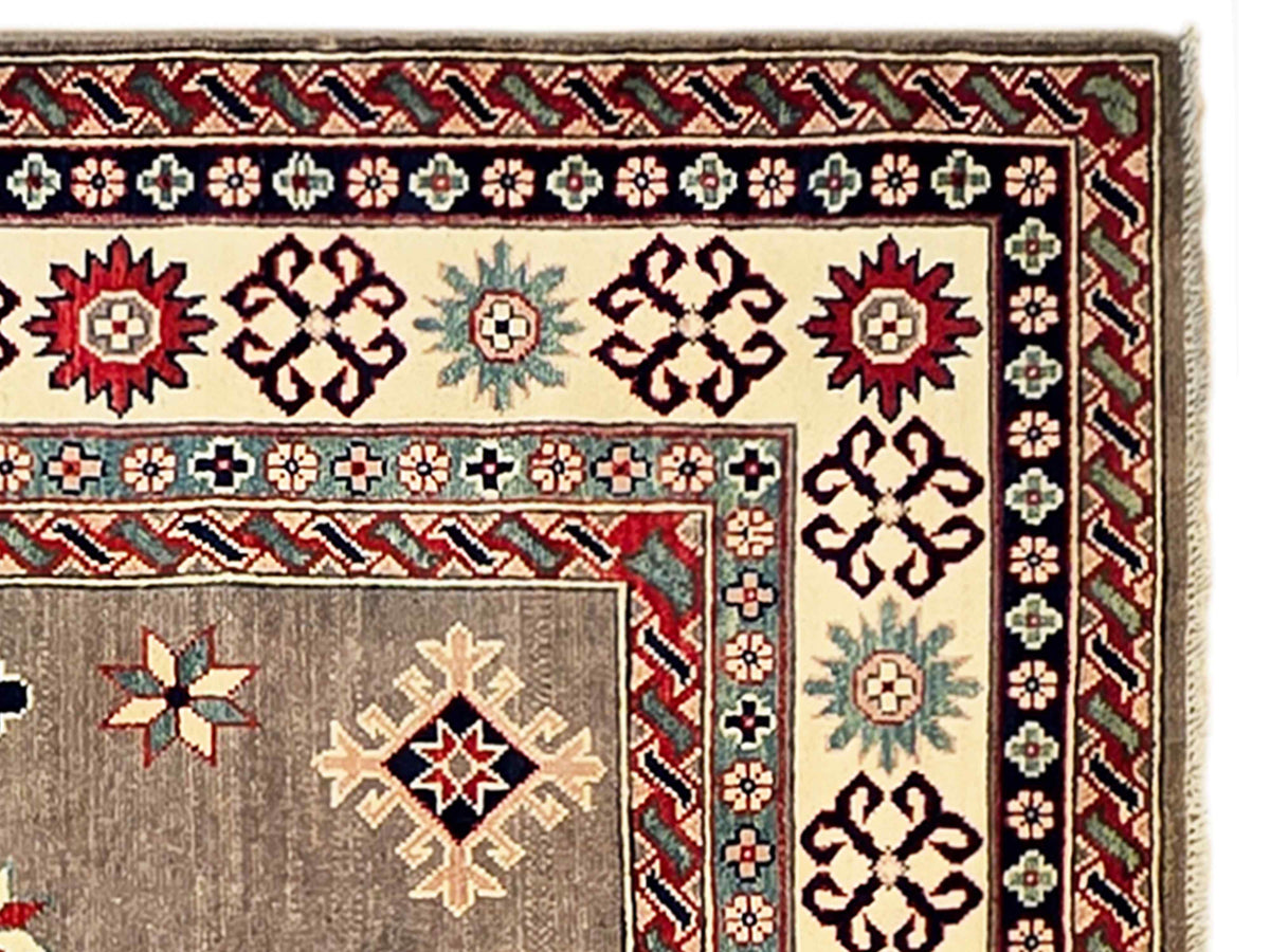 Kazak rug close-up showing beige-gray field, red and blue border details, and fringe