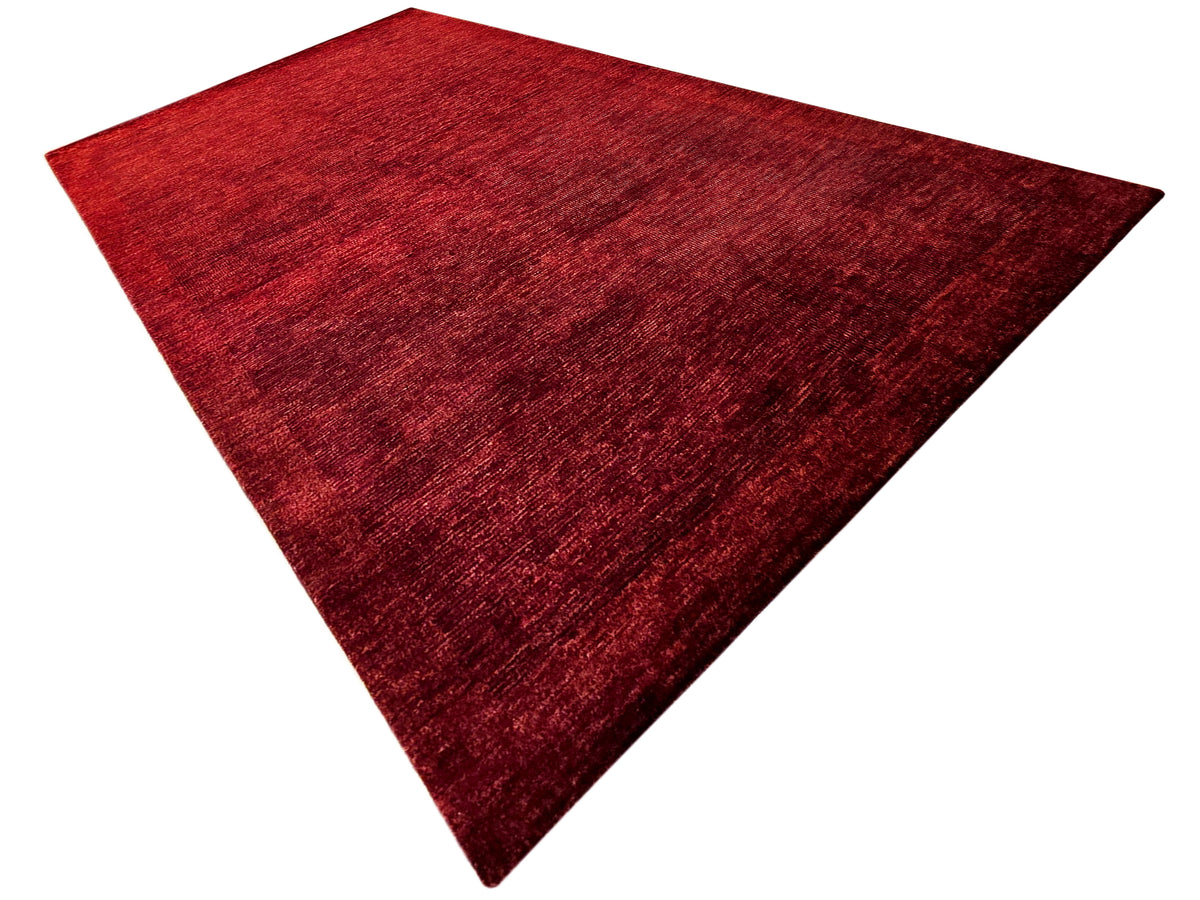 Red area rug with abstract textured surface, triangular angled view
