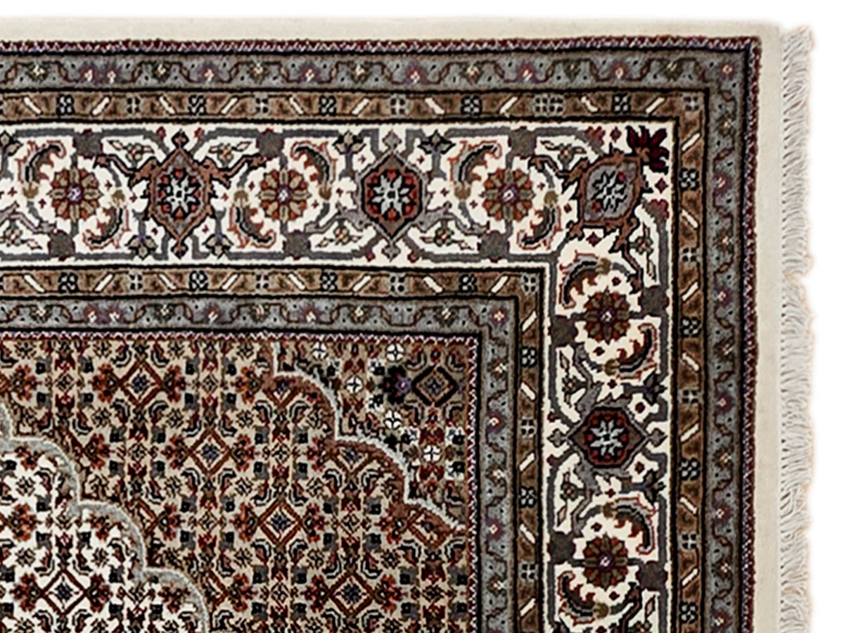 Close-up of detailed patterned area rug with geometric motifs and fringed trim.