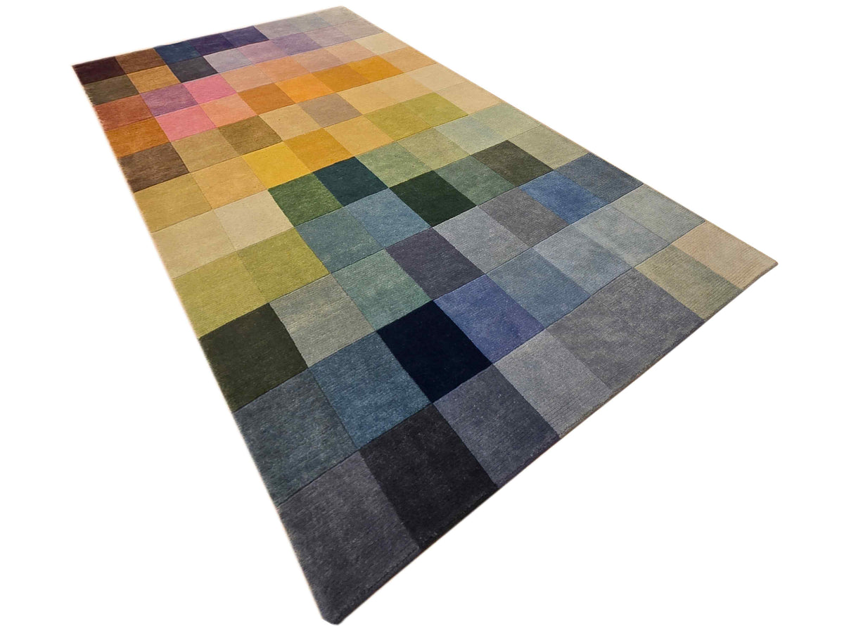 Diagonal view of multicolor square-block rug with blue, green, tan, and dark navy