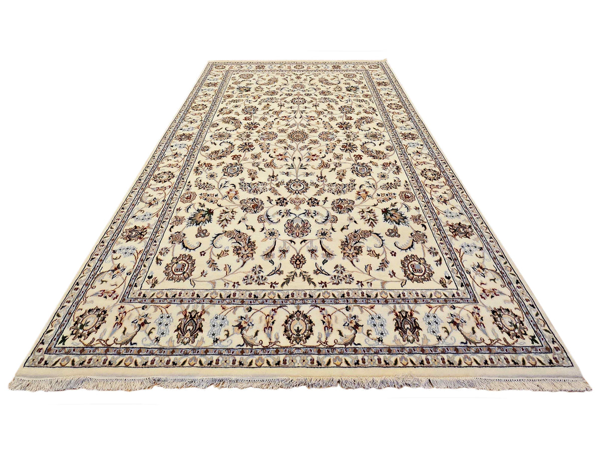 Cream area rug with ornate floral medallion border in blue and dark accents, fringed edges