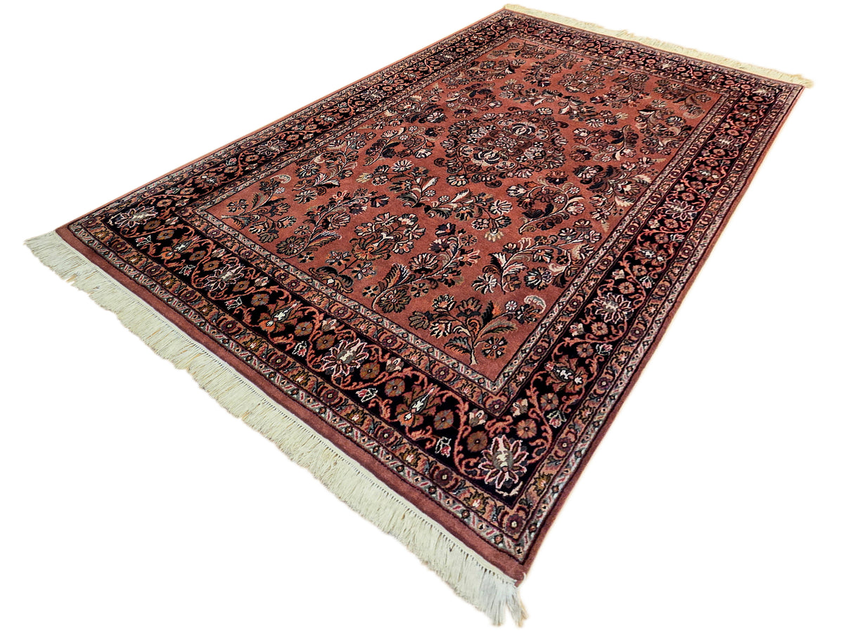 Terracotta rug with dark floral centerpiece and geometric border, fringed corners