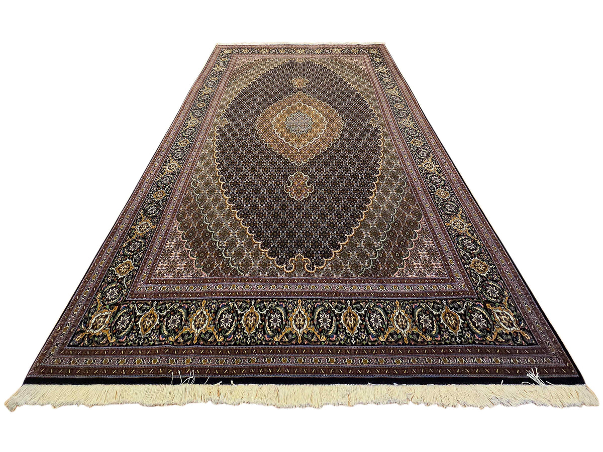 Dark Tabriz-style rug with central medallion and cream fringe along lower edge