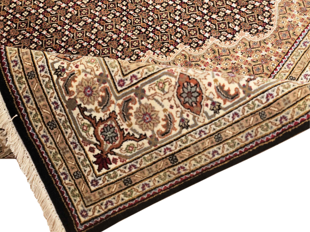 Ornate Tabriz mahi rug with cream field, dark border, and floral medallions
