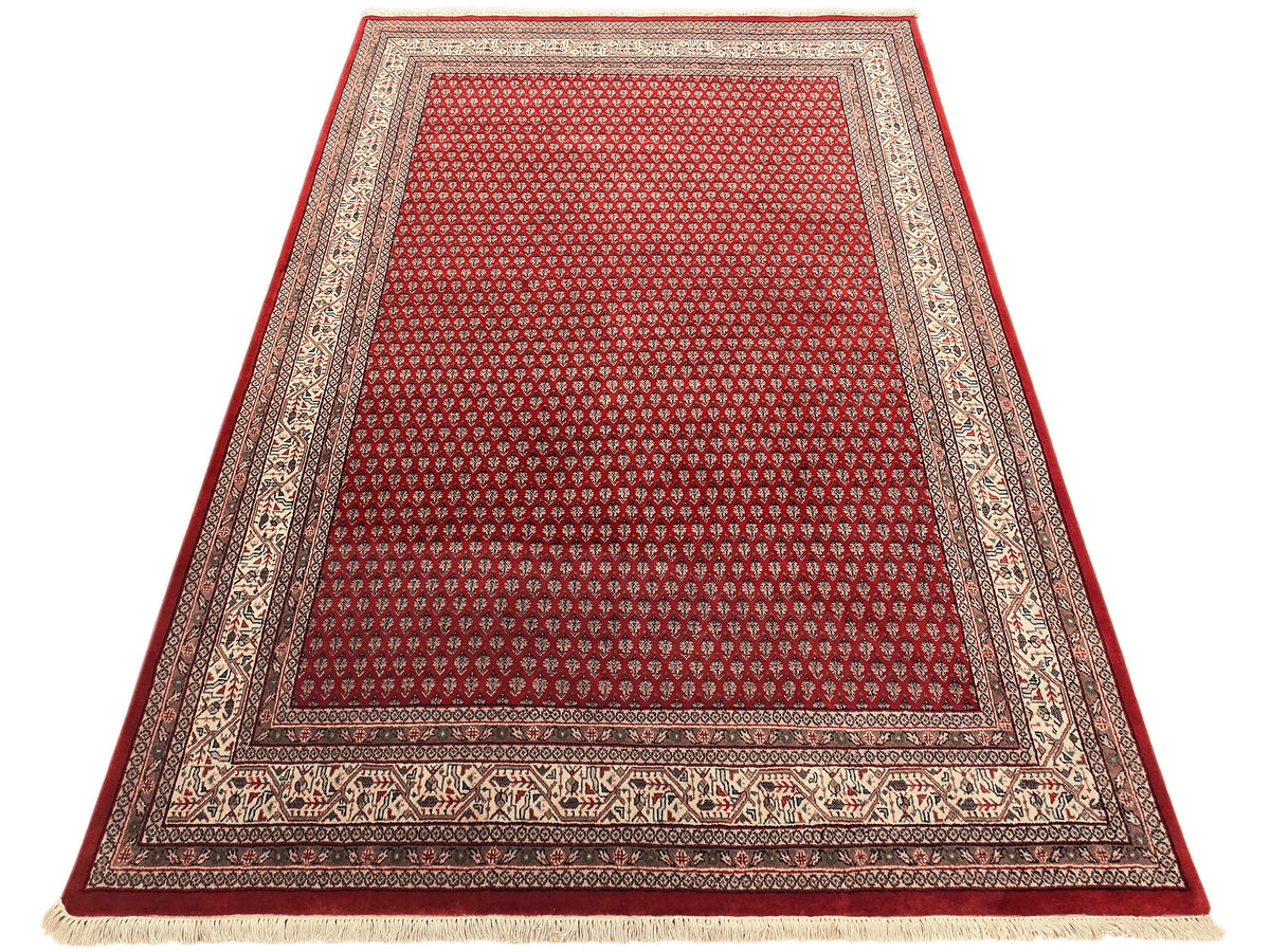 Red area rug with central lattice motif and detailed cream border, short fringe.