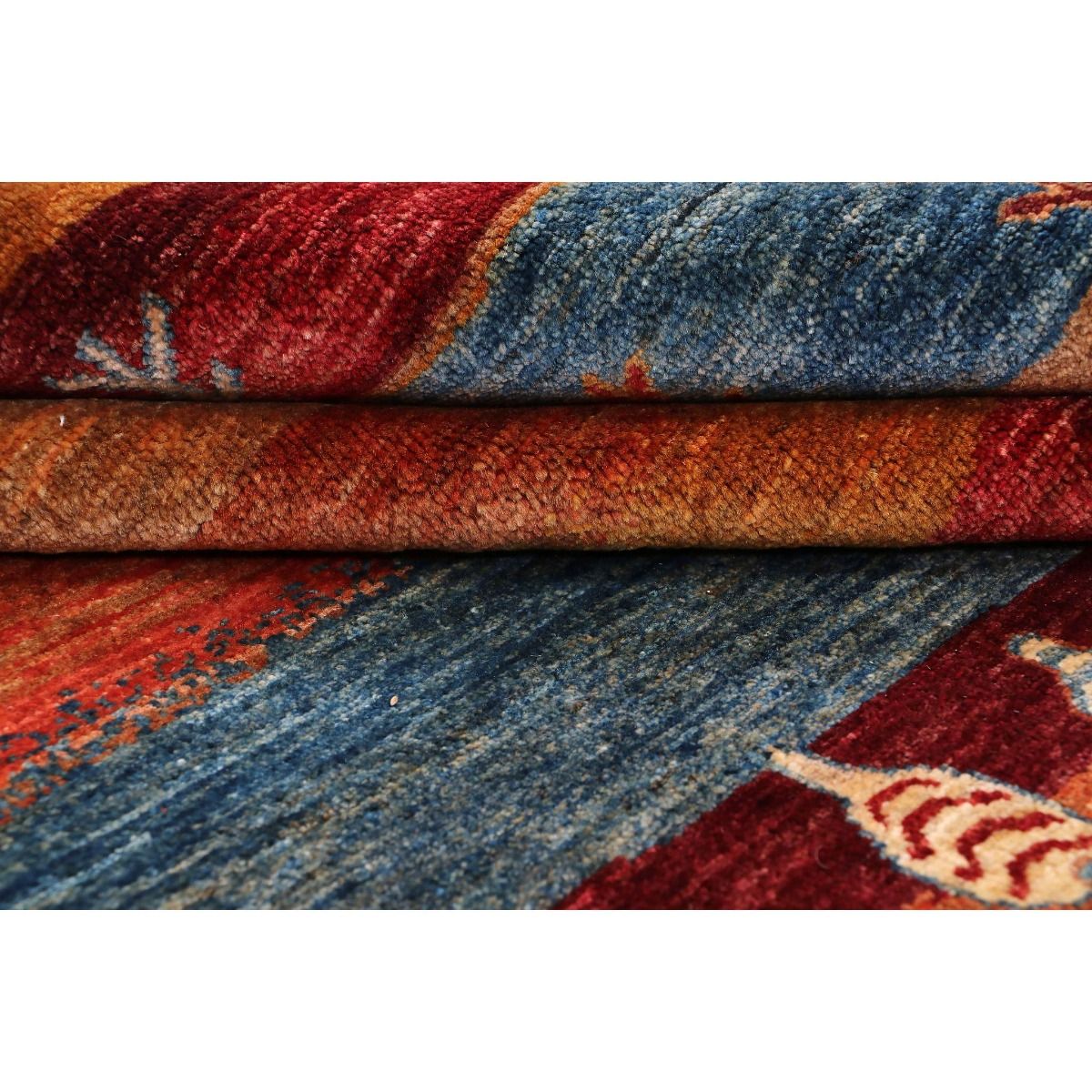 Stacked rug edge close-up showing layered texture in red, blue, and beige