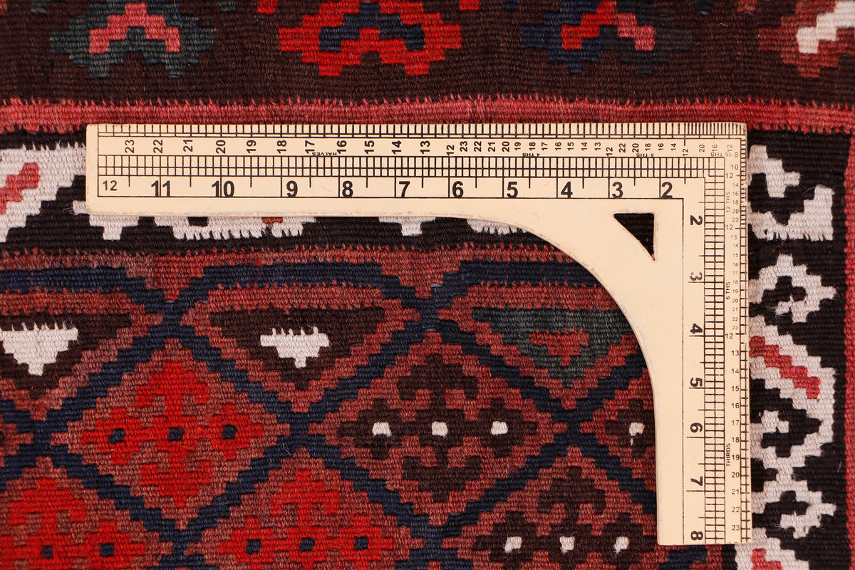 Measuring tape on red and black kilim rug edge, showing size marks