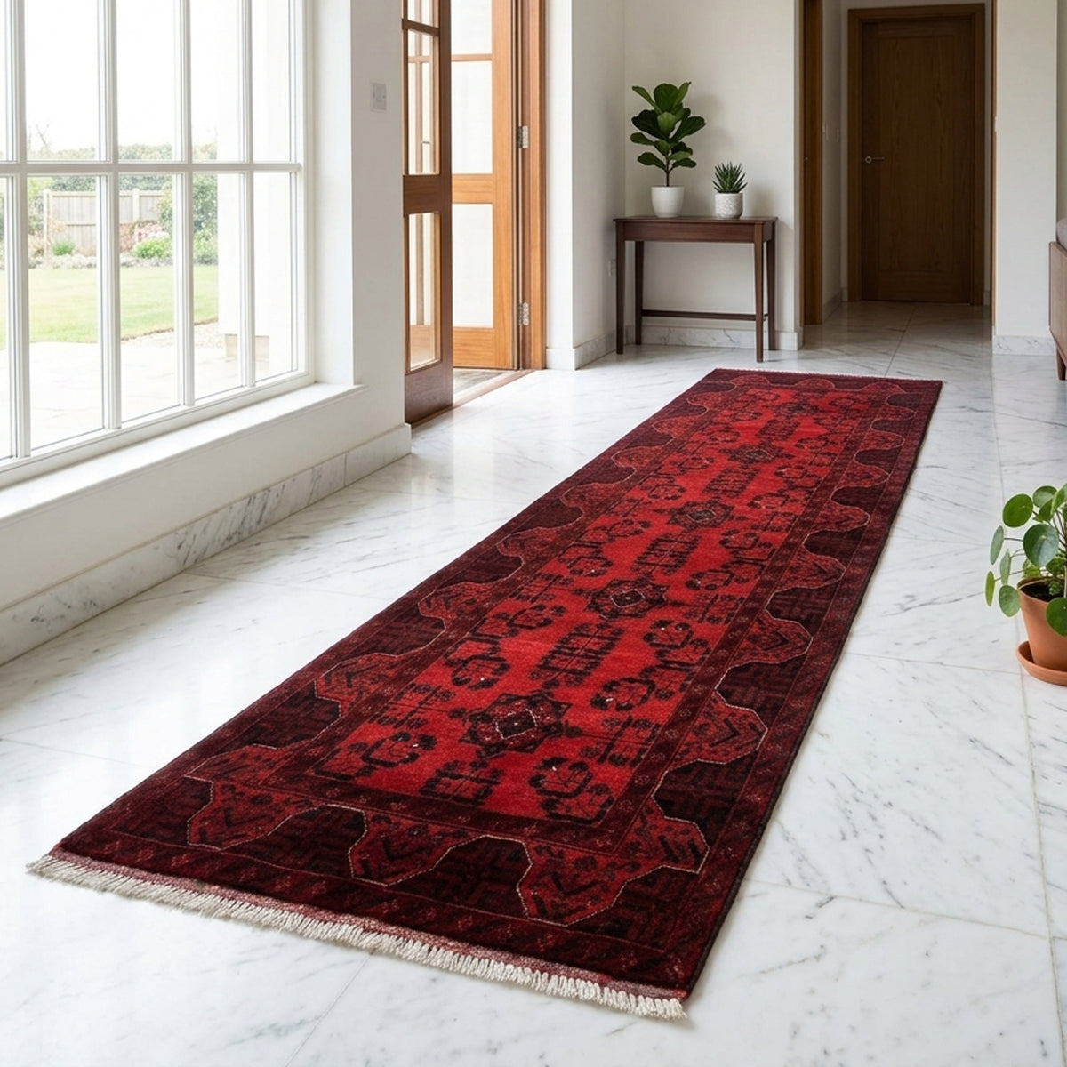 Red runner rug with dark geometric pattern and tan fringe along the edges