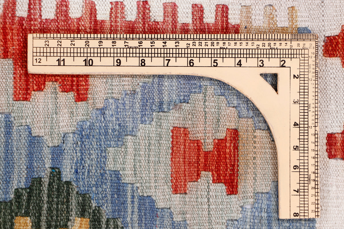 Kilim rug detail with ruler measuring stitch and blue geometric shapes