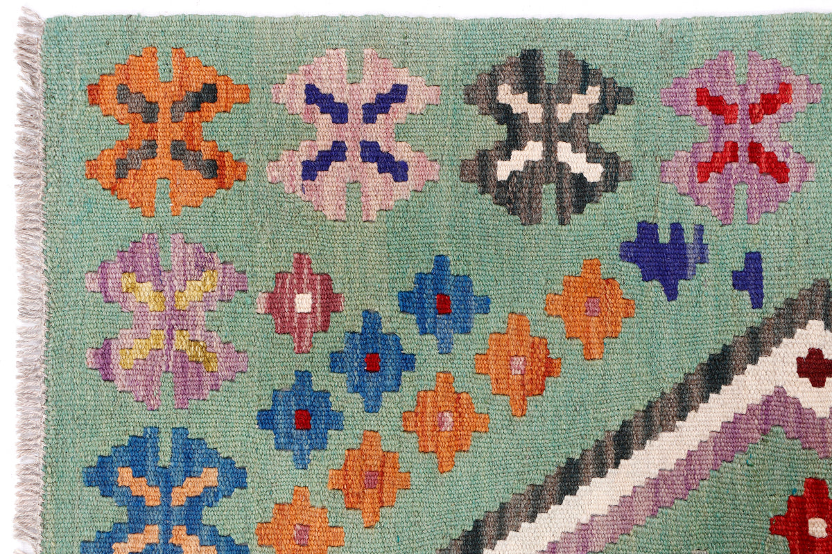 Green kilim rug with colorful star and cross motifs, textured flatwoven weave