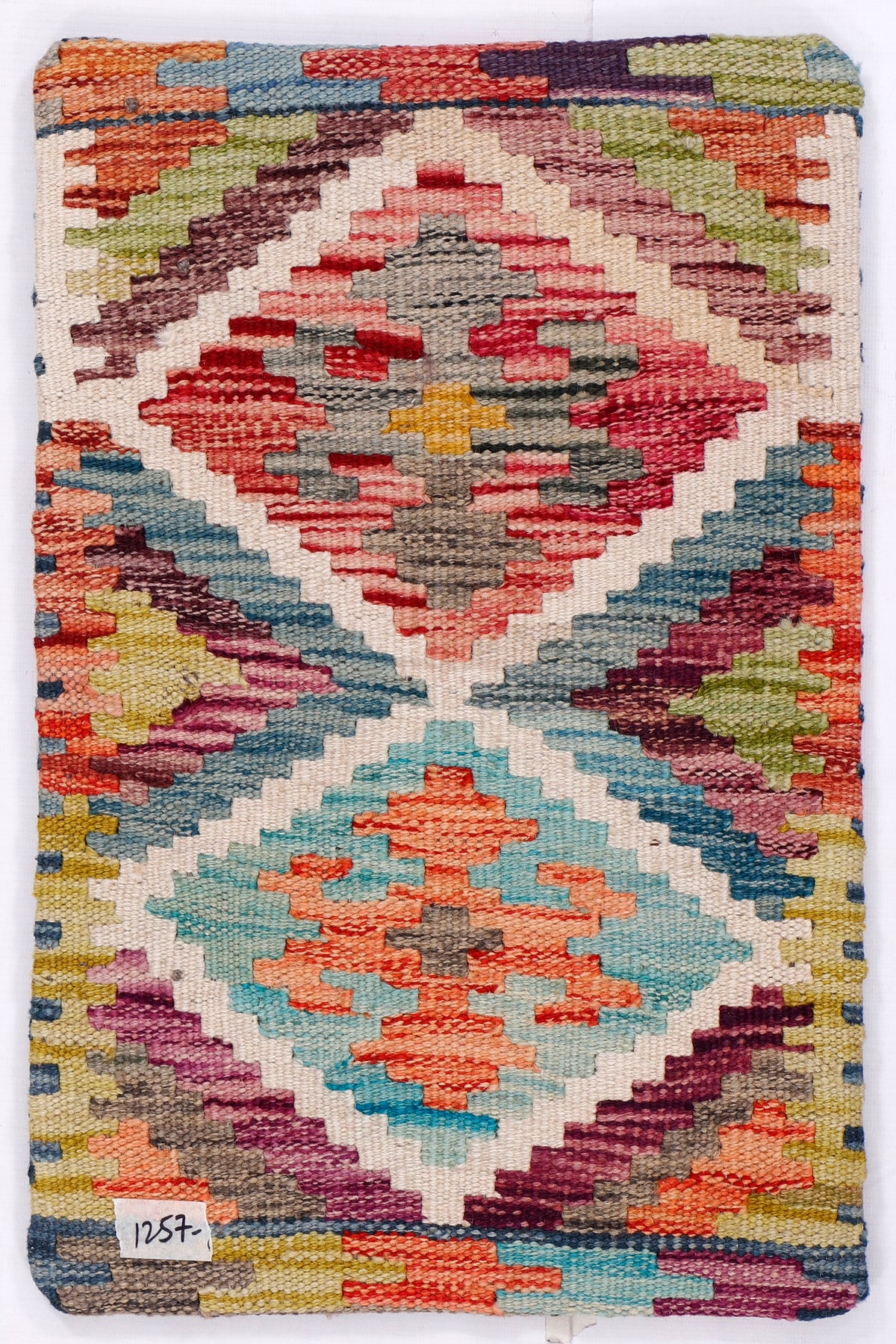 Kilim cushion cover with colorful geometric diamonds and border, close-up woven texture