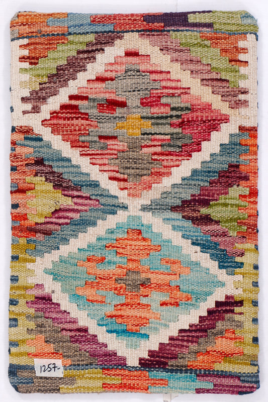 Kilim cushion cover with colorful geometric diamonds and border, close-up woven texture