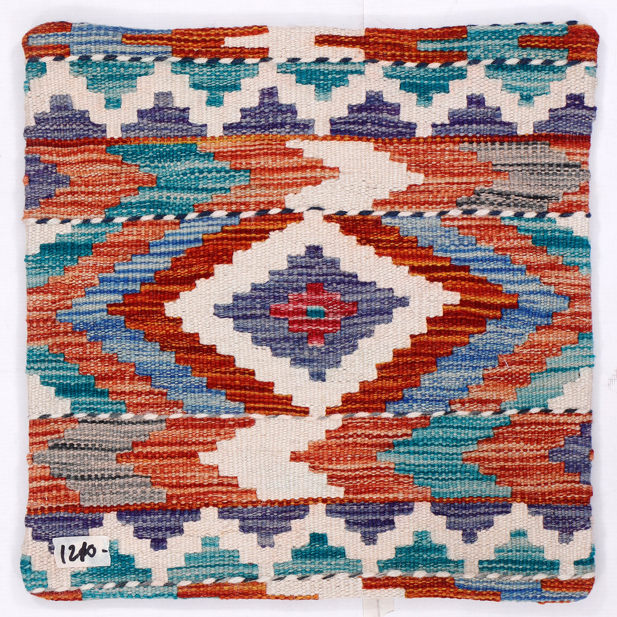 Kilim cushion cover close-up with blue, orange, teal geometric motifs on cream background