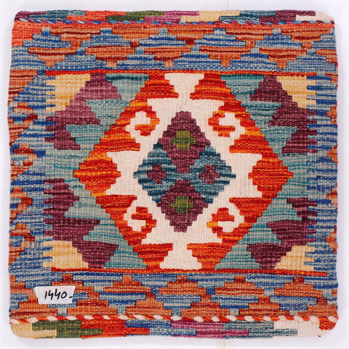Kilim cushion cover close-up with orange, blue, white, and burgundy geometric medallion
