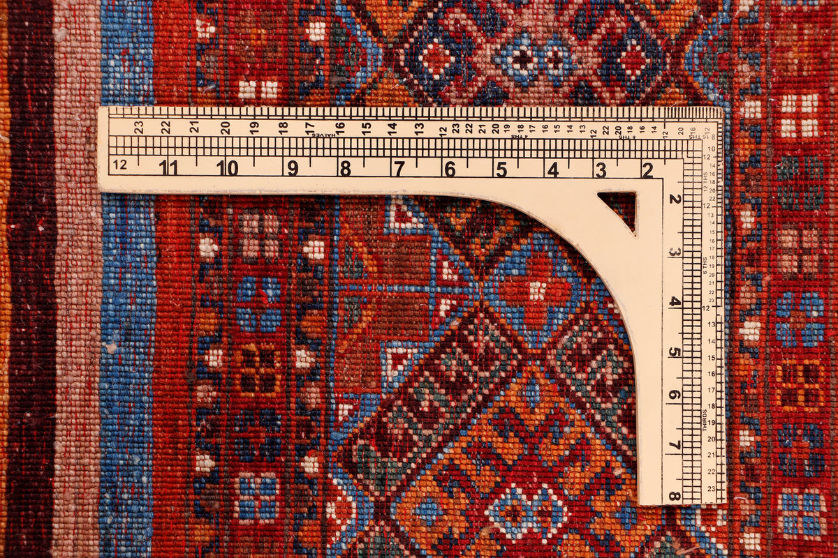 Multicolor geometric rug with diamond motifs and red border, close-up