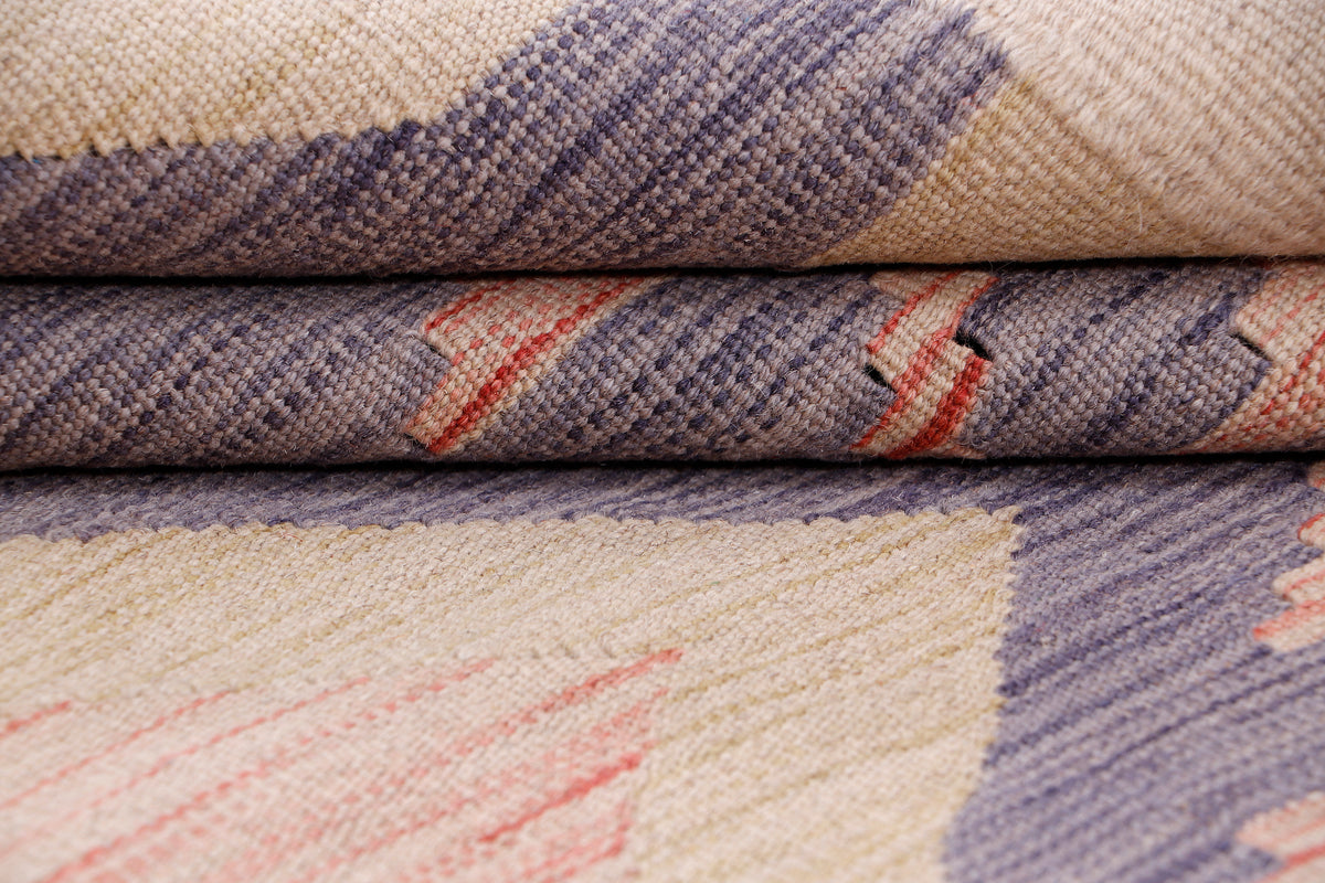Rolled kilim rug edge with woven texture and purple, peach, and cream geometric print.