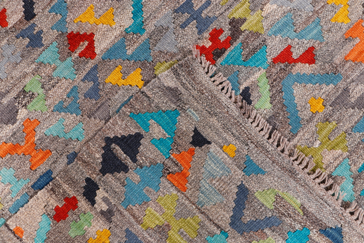 Kelim rug section with multicolor diamond and star motifs on a gray weave