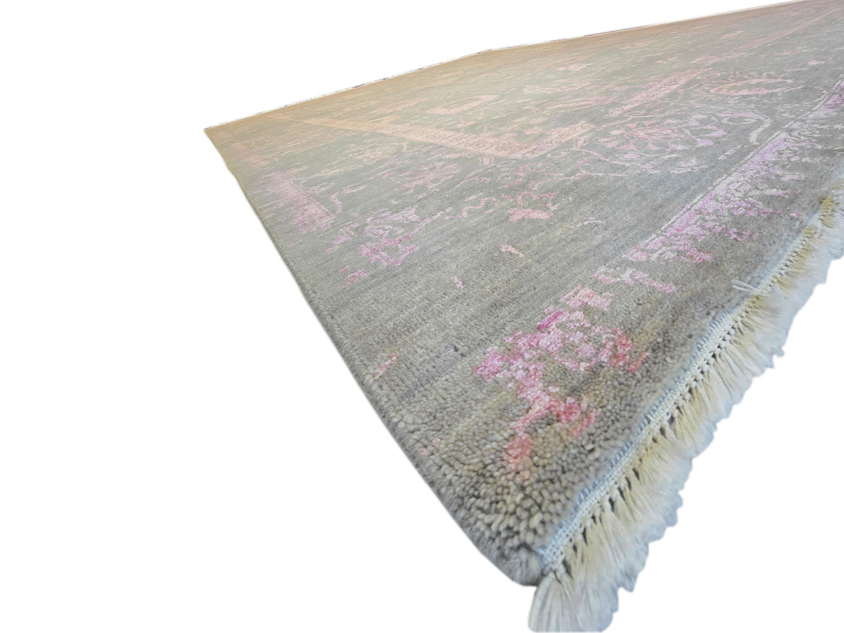 Modern rug corner with short fringe; gray with faded pink decorative pattern