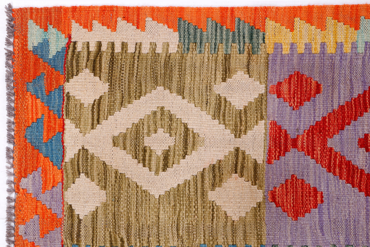 Kilim rug close-up with fringed edge and diamond motifs in orange, blue, beige and purple