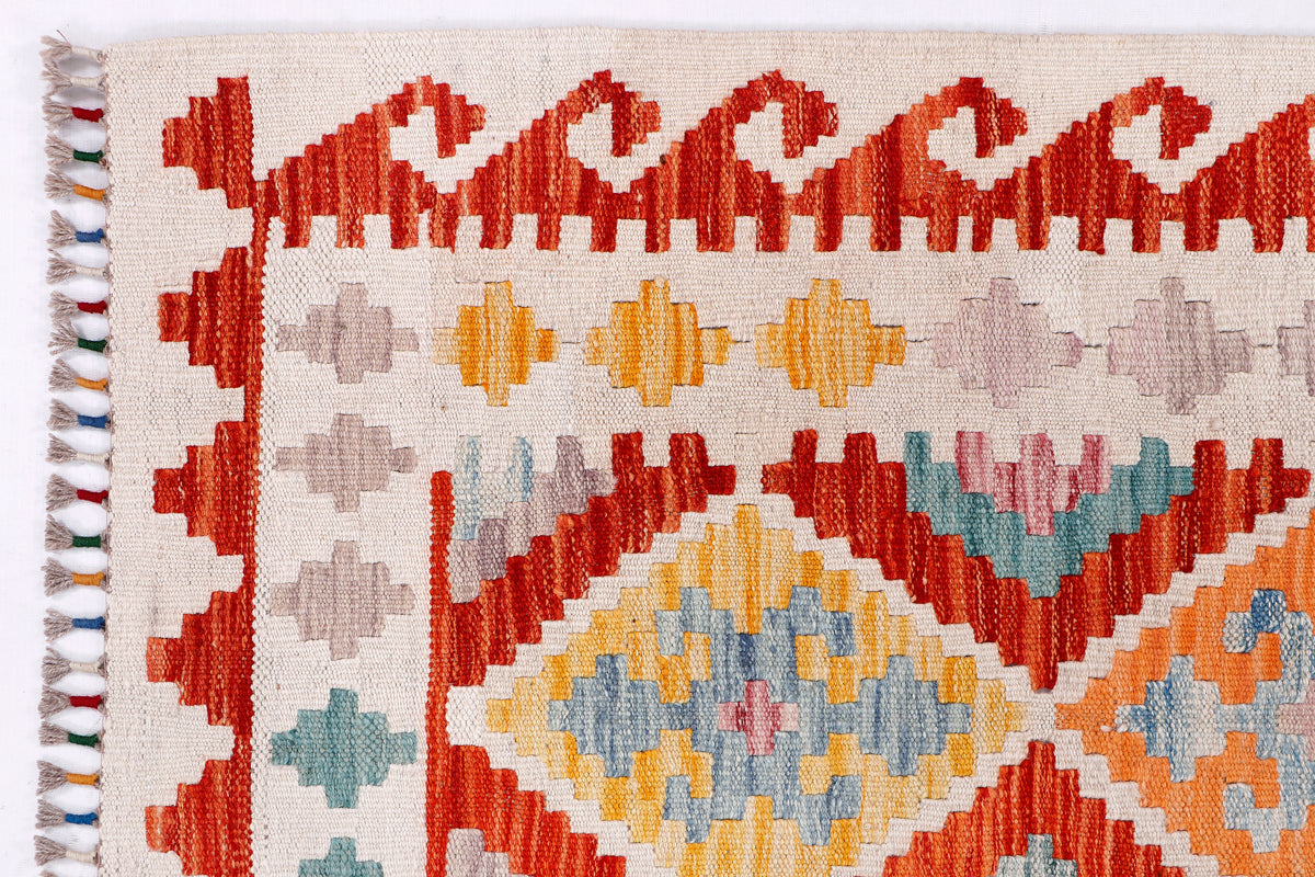 Kilim rug edge with tassel fringe and bold geometric bands, close-up.