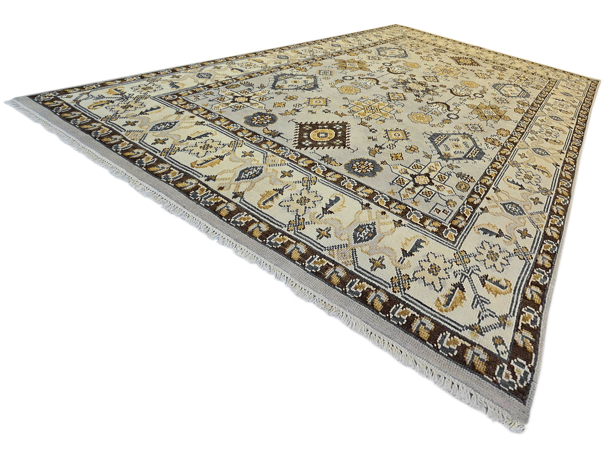 Rectangular Oushak rug with pale ivory field, dark navy borders, ornate medallion pattern.